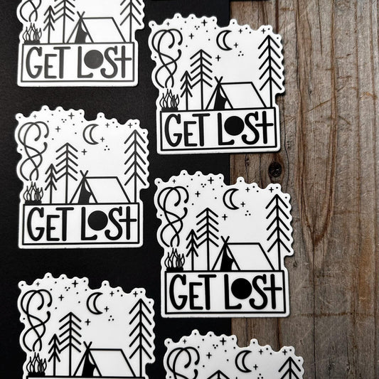 Set of 'GET LOST' themed stickers on a wooden surface
