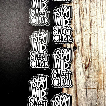 Stickers with 'Stay Wild, Sweet Child' text on a wooden surface