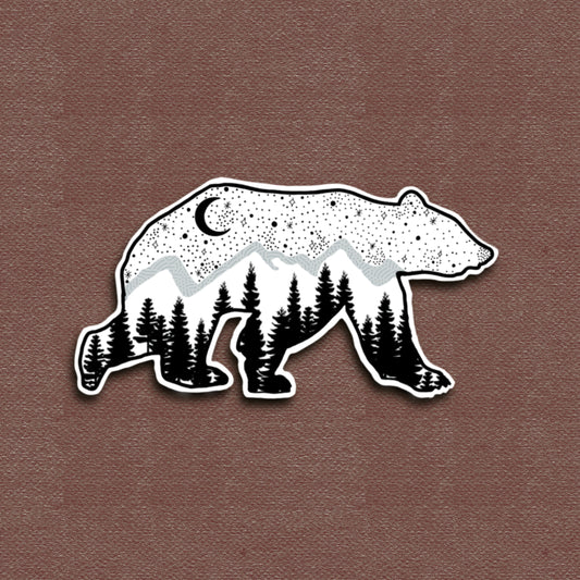 A matte vinyl decal of a bear with a galaxy pattern, featuring trees and a crescent moon in a black and white color scheme.