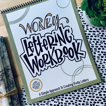 Creative desk setup with Wonky Letters workbook, pens, tea, and doodles in progress