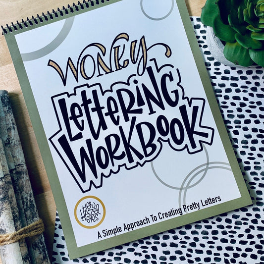 Creative desk setup with Wonky Letters workbook, pens, tea, and doodles in progress