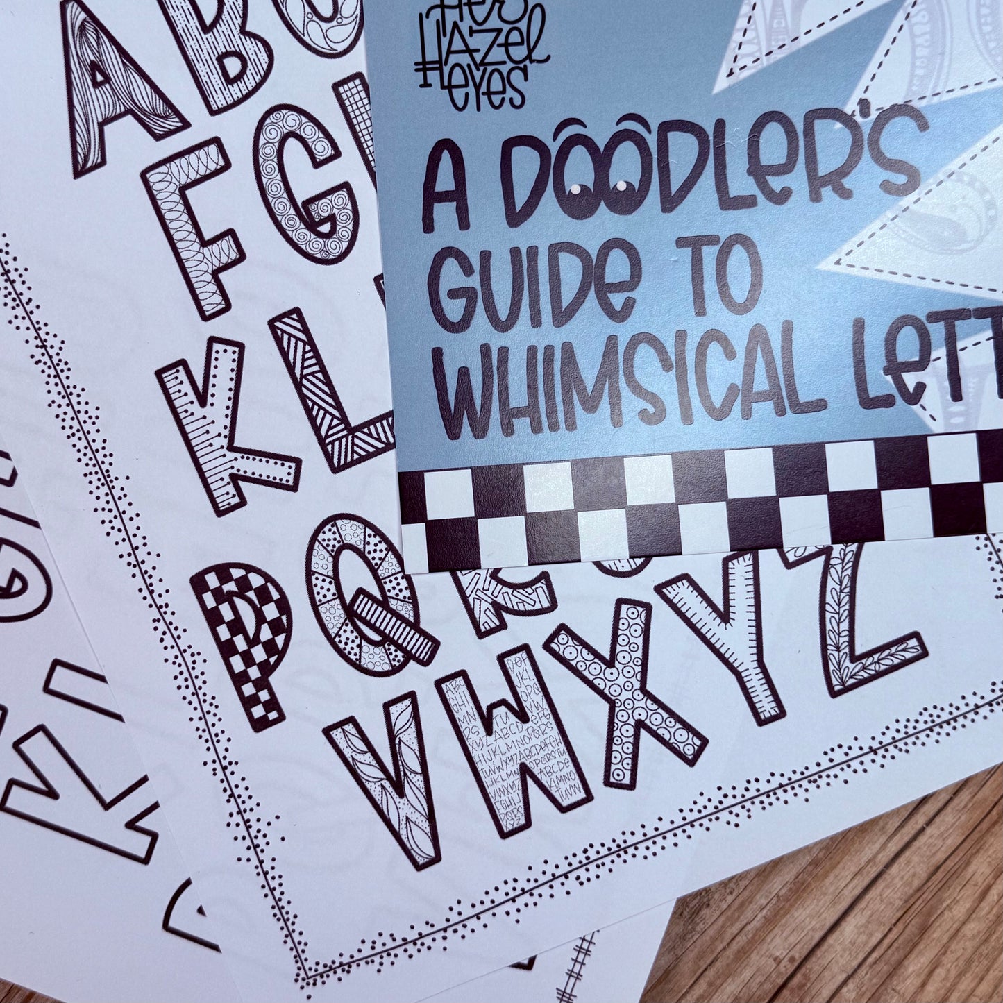 Lettering workbook open to whimsical alphabet examples and lined practice sheets