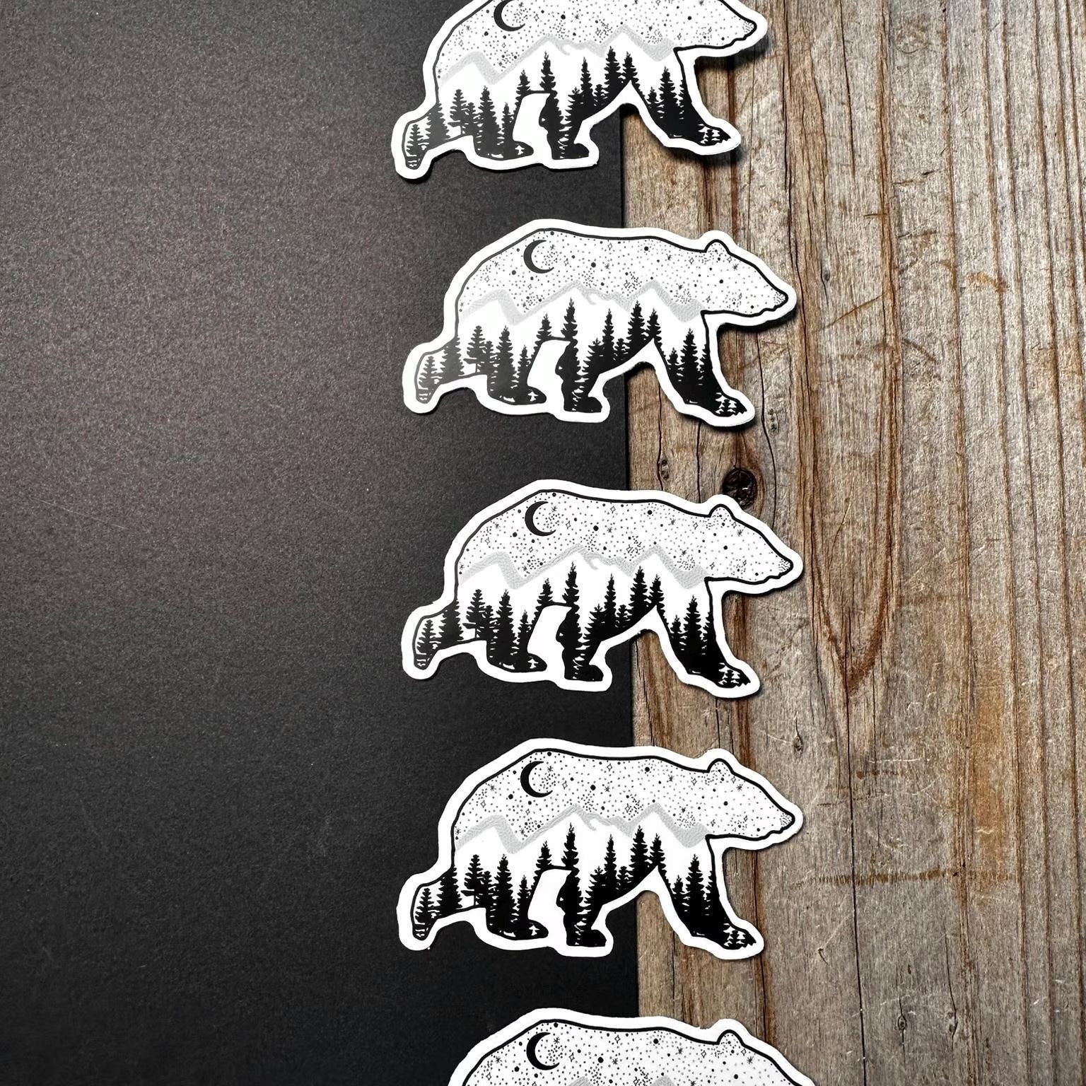 Set of bear-themed stickers with forest design on a wooden surface
