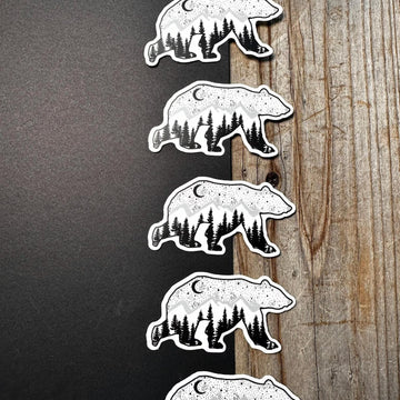 Set of bear-themed stickers with forest design on a wooden surface