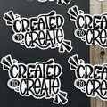Sticker with 'Created to Create' text on a black background and wooden surface.