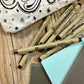 Micron pens arranged beside dotted notebook and lettering workbook on desk