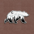 A matte vinyl decal of a bear with a galaxy pattern, featuring trees and a crescent moon in a black and white color scheme.