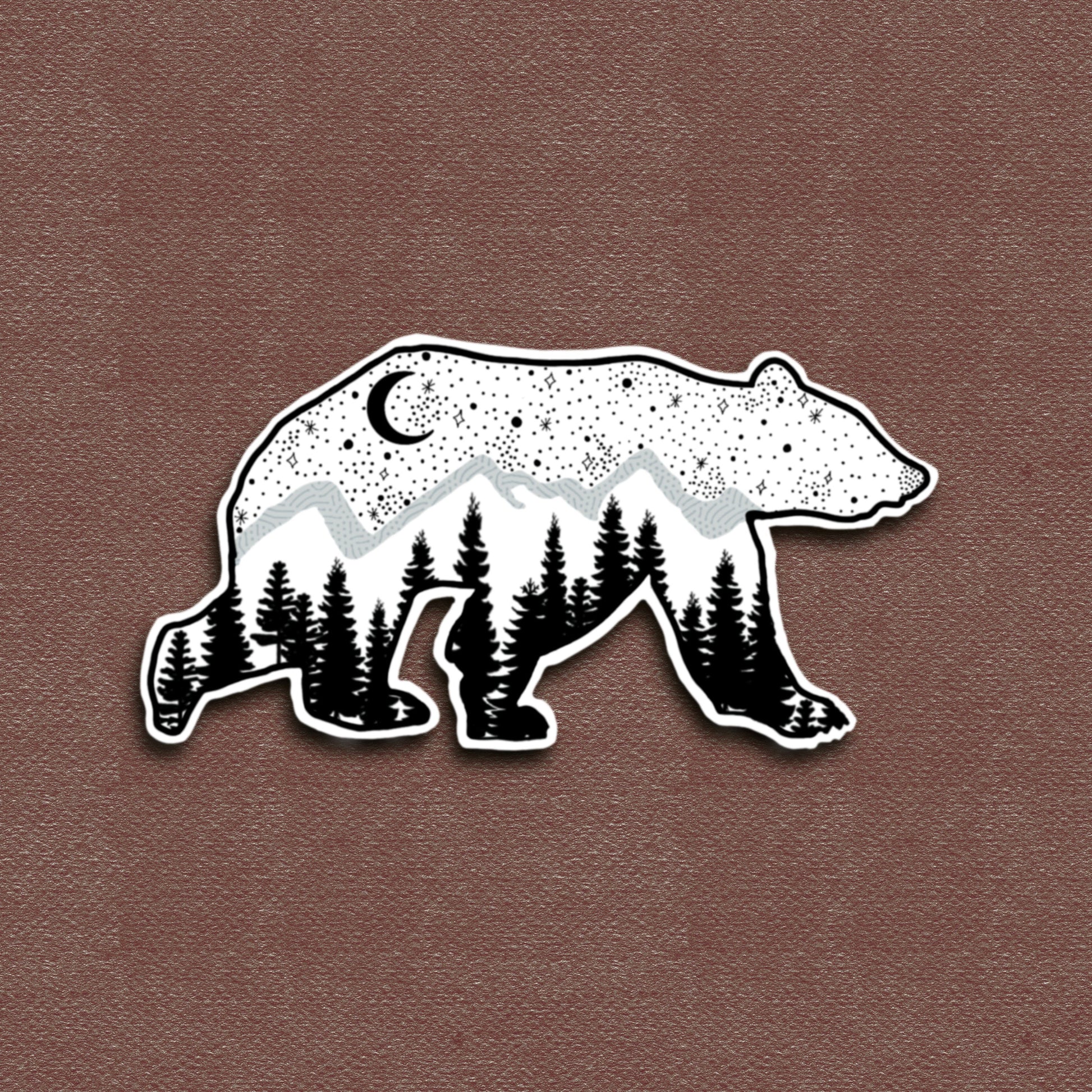 A matte vinyl decal of a bear with a galaxy pattern, featuring trees and a crescent moon in a black and white color scheme.