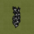A matte vinyl decal sticker with a tattoo flower design, black and white in color, placed on a green background.